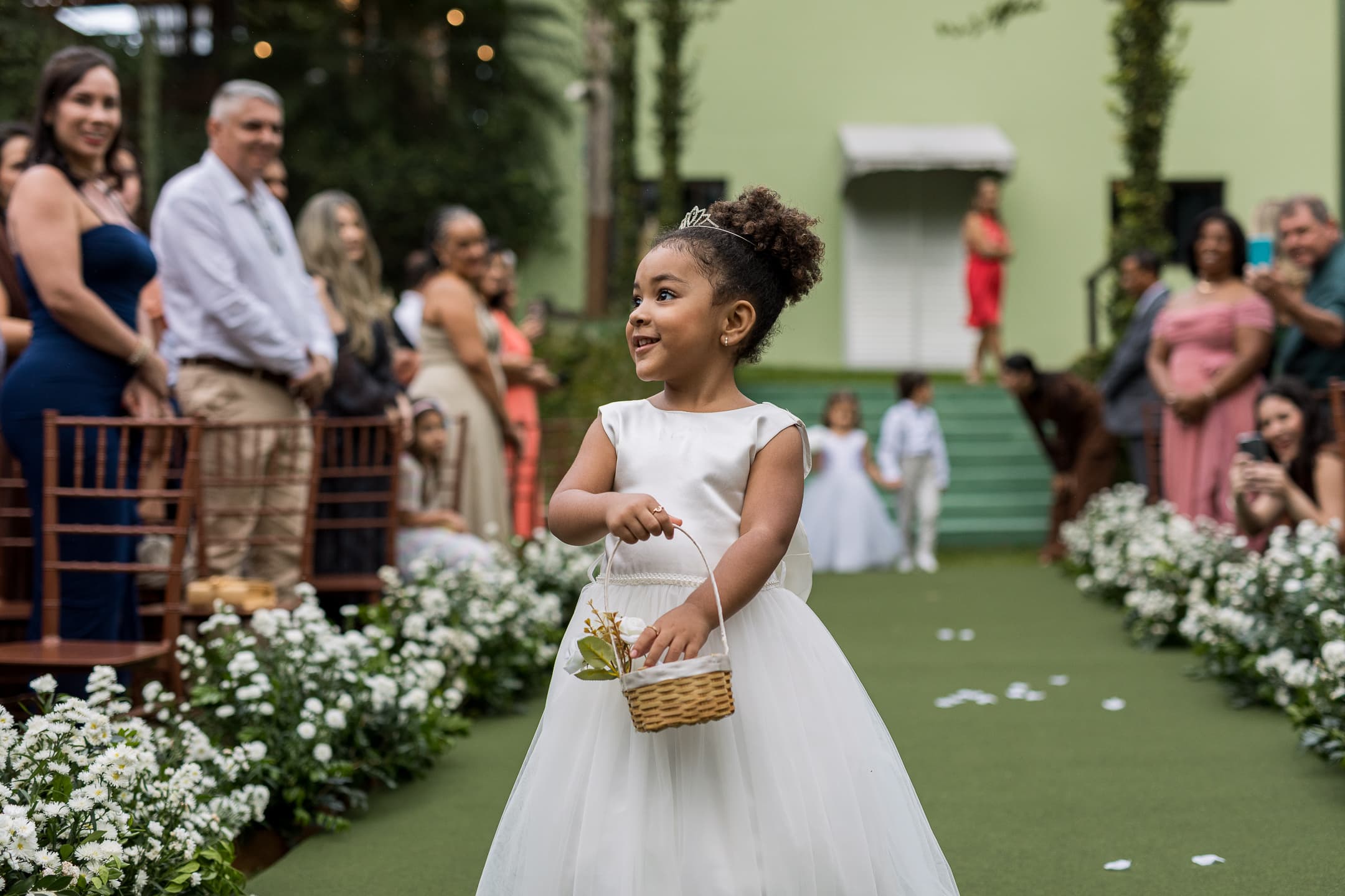 Daminha sorrindo ao descer o corredor com a cestinha de flores