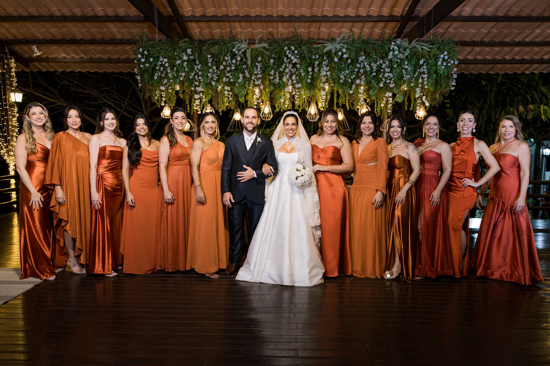 Madrinhas em vestidos terracota ao lado dos noivos no salão