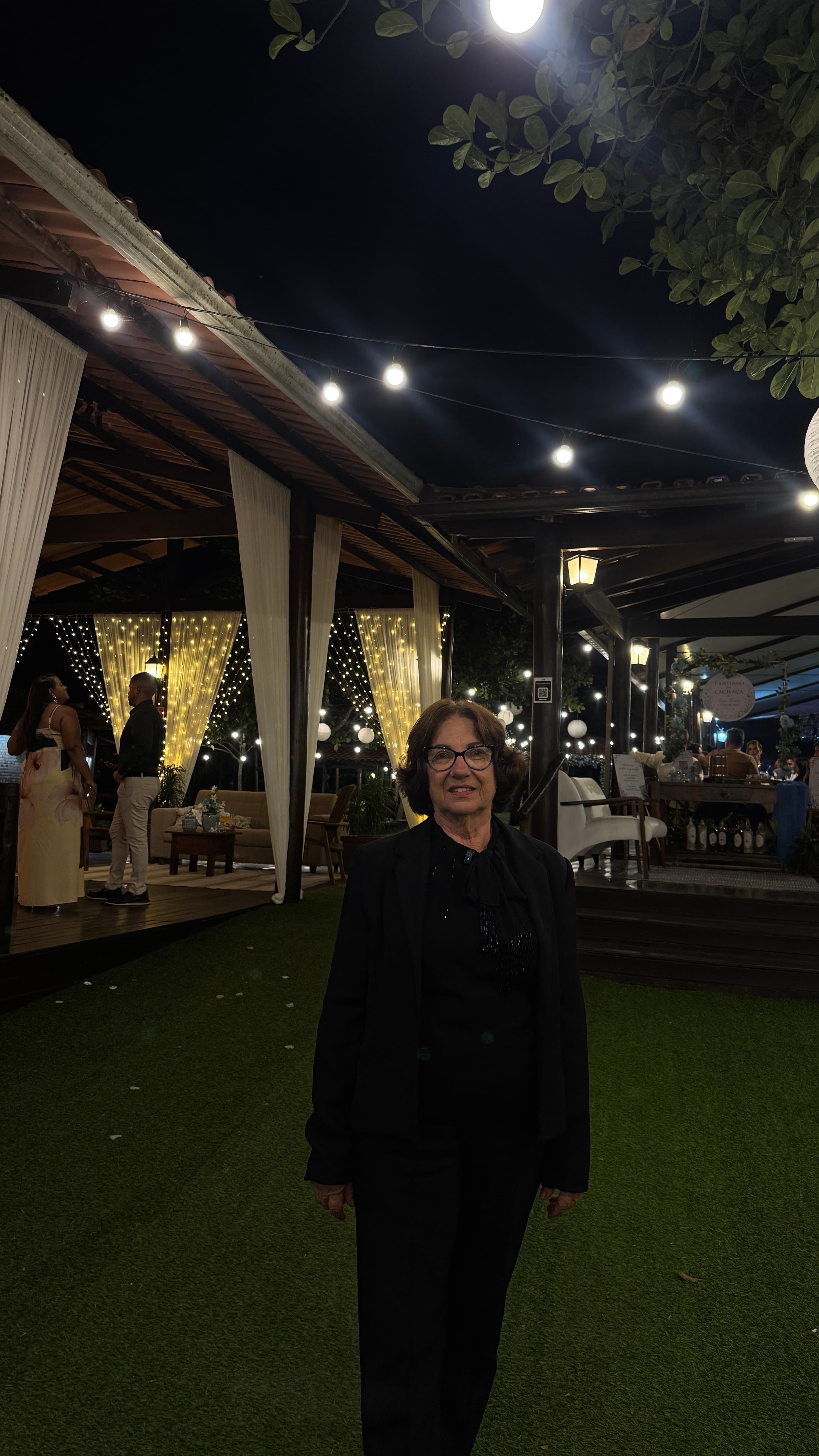 Dona Lúcia, a Nona Lú, no salão durante uma celebração à noite