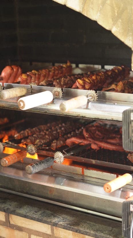 Churrasqueira giratória da casa com carnes assando sobre a brasa